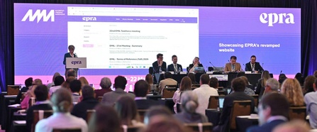 Blick auf den Konferenzsaal während des 63. Treffens der European Platform of Regulatory Authorities (EPRA). Im Vordergrund sitzen Teilnehmende, auf der Bühne findet eine Präsentation mit Paneldiskussion statt.