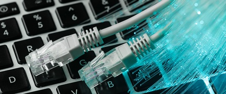 Ethernet Kabeln mit RJ45 Anschlüssen auf einer Tastatur neben  Fasern