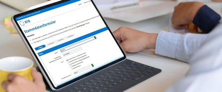 Eine Person sitzt mit einem Tablet am Tisch, am Bildschirm ist das Stammdatenformular der RTR-GmbH zu sehen
