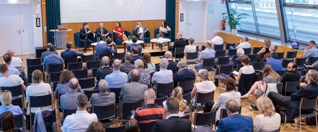 Saal in der Wiener Urania mit Publikum und Podiumsgästen aus der Vogelperspektive von hinten