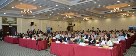 Teilnehmende sitzen an Tischen in Konferenzraum