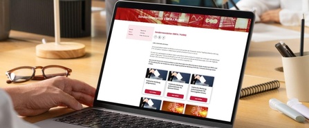 Ein Laptop am Tisch. Hände daneben. Auf dem Bildschirm der Sondernewsletter. 