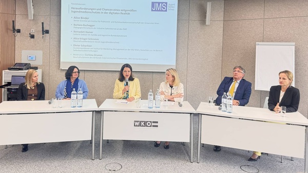 Die Podiumsgäste sitzen an drei nebeneinanderstehenden Tischen. Alice Binder (Kommunikationswissenschaften Uni Wien, Barbara Buchegger (Saferinternet.at), Corinna Drumm (Moderation, VÖP), Bernadett Humer (Lt. BKA Sektion VI, Familie u. Jugend), Dieter Scharitzer (WU Wien), Alice Krieger-Schromm (GF JMS)