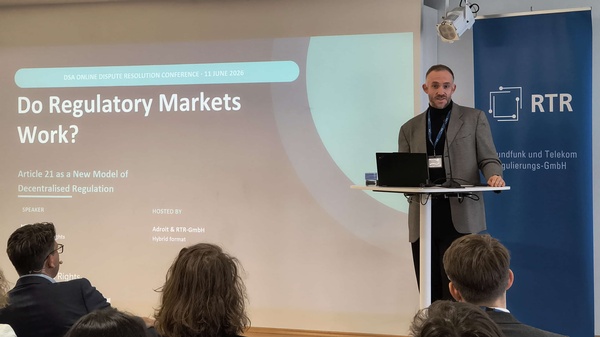 Referent präsentiert einen Vortrag zu regulatorischen Märkten und Artikel 21 DSA vor dem Publikum.