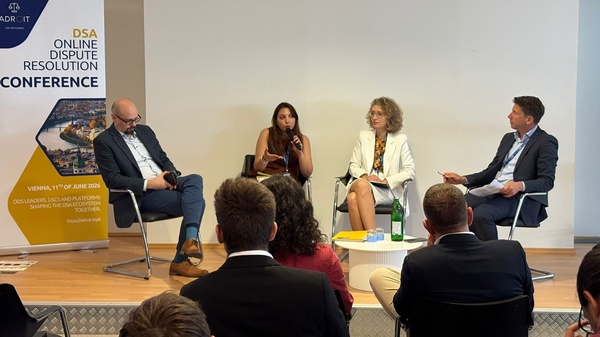 Drei Diskussionsteilnehmende und der Moderator sitzen auf dem Podium und diskutieren vor dem Publikum.