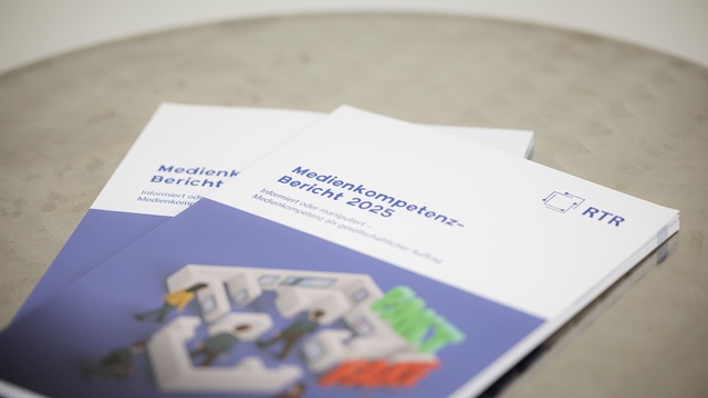 Nahaufnahme von zwei gedruckten Medienkompetenzberichten 2025 der RTR, die übereinander auf einem Tisch liegen.