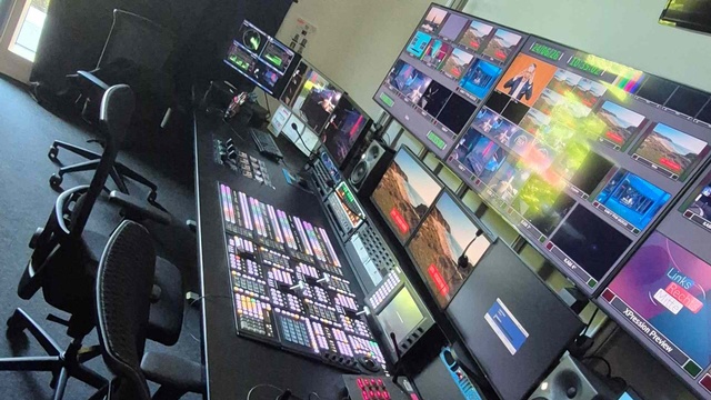 Regieraum des Fernsehstudios. Mehrere Monitore und ein großes Mischpult für die Steuerung und Überwachung von Video- und Audiosignale.