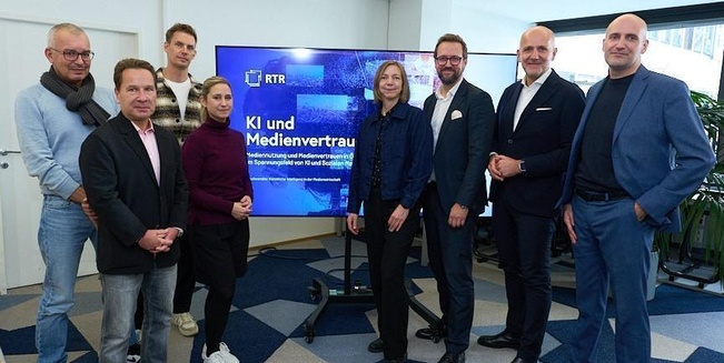 Redner und Podiumsgäste der Veranstaltung, fotografiert vor einem großen Monitor, auf dem das Titelbild der Studie zu sehen ist.