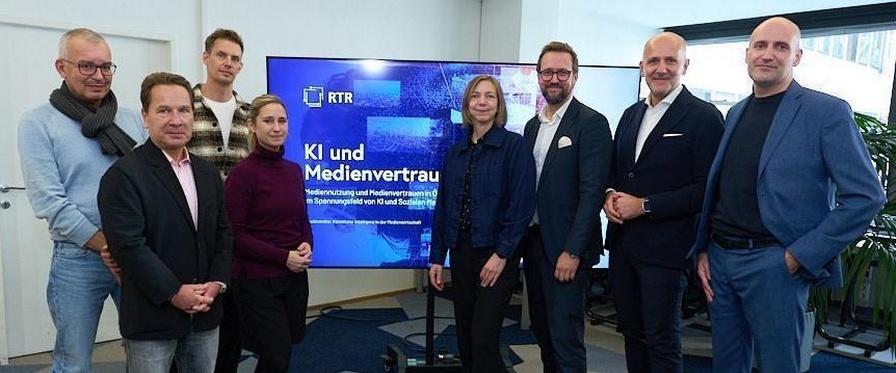 Redner und Podiumsgäste der Veranstaltung, fotografiert vor einem großen Monitor, auf dem das Titelbild der Studie zu sehen ist.