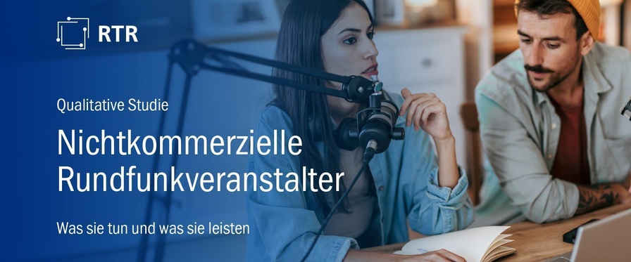 Eine junge Frau und ein junger Mann an einem Tisch. Ein professionelles Mikrofon an einem Stativ. Ein Laptop auf dem Tisch. Im Hintergrund Regale und eine Zimmerpflanze, die eher Wohnzimmeratmosphäre vermitteln.