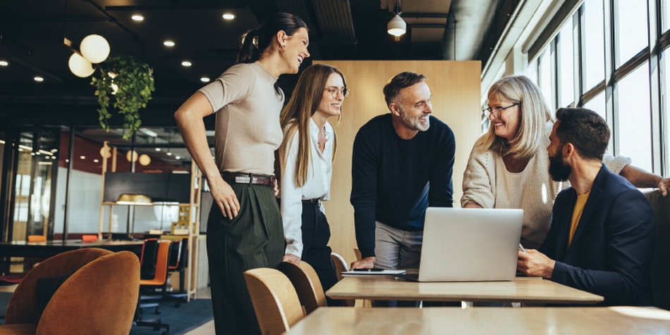 Kolleg:innen um Schreibtisch